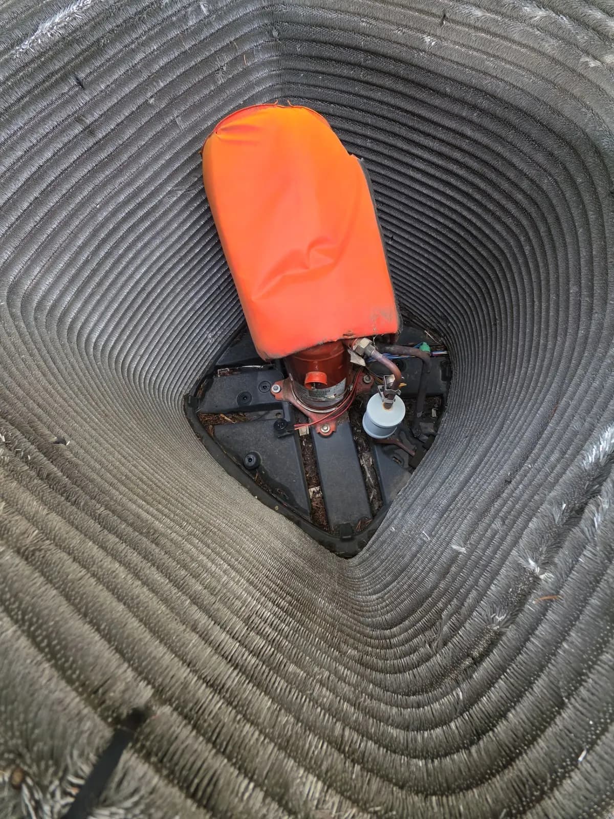 Inside view of an open AC condenser showing the compressor wrapped in an orange sound blanket
