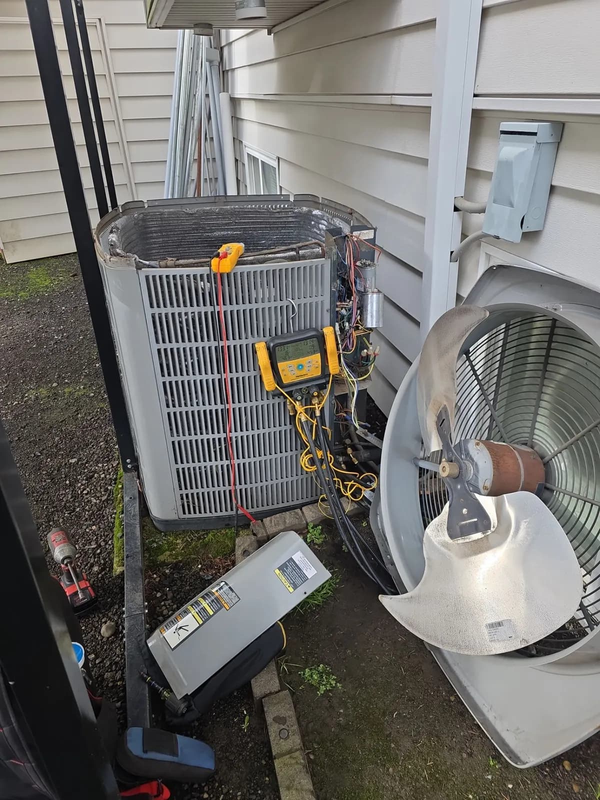 Outdoor AC condenser with the fan top removed and digital refrigerant gauges connected