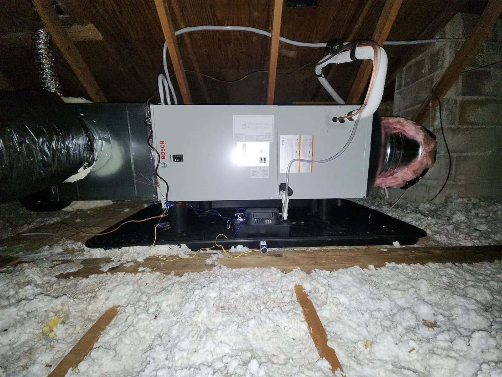 New air handler installed on a platform in an insulated attic with connected ductwork