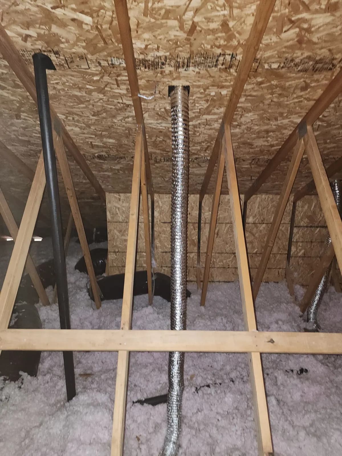 Insulated flex duct running down through attic trusses over blown-in insulation