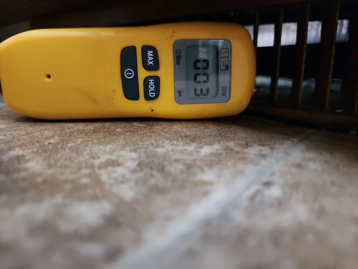 Yellow carbon monoxide meter at a floor register reading 3 ppm