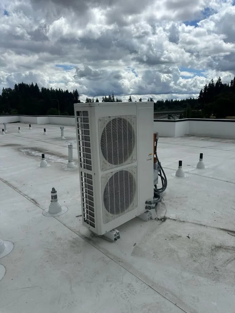 Large two-fan heat pump outdoor unit on a white commercial flat roof