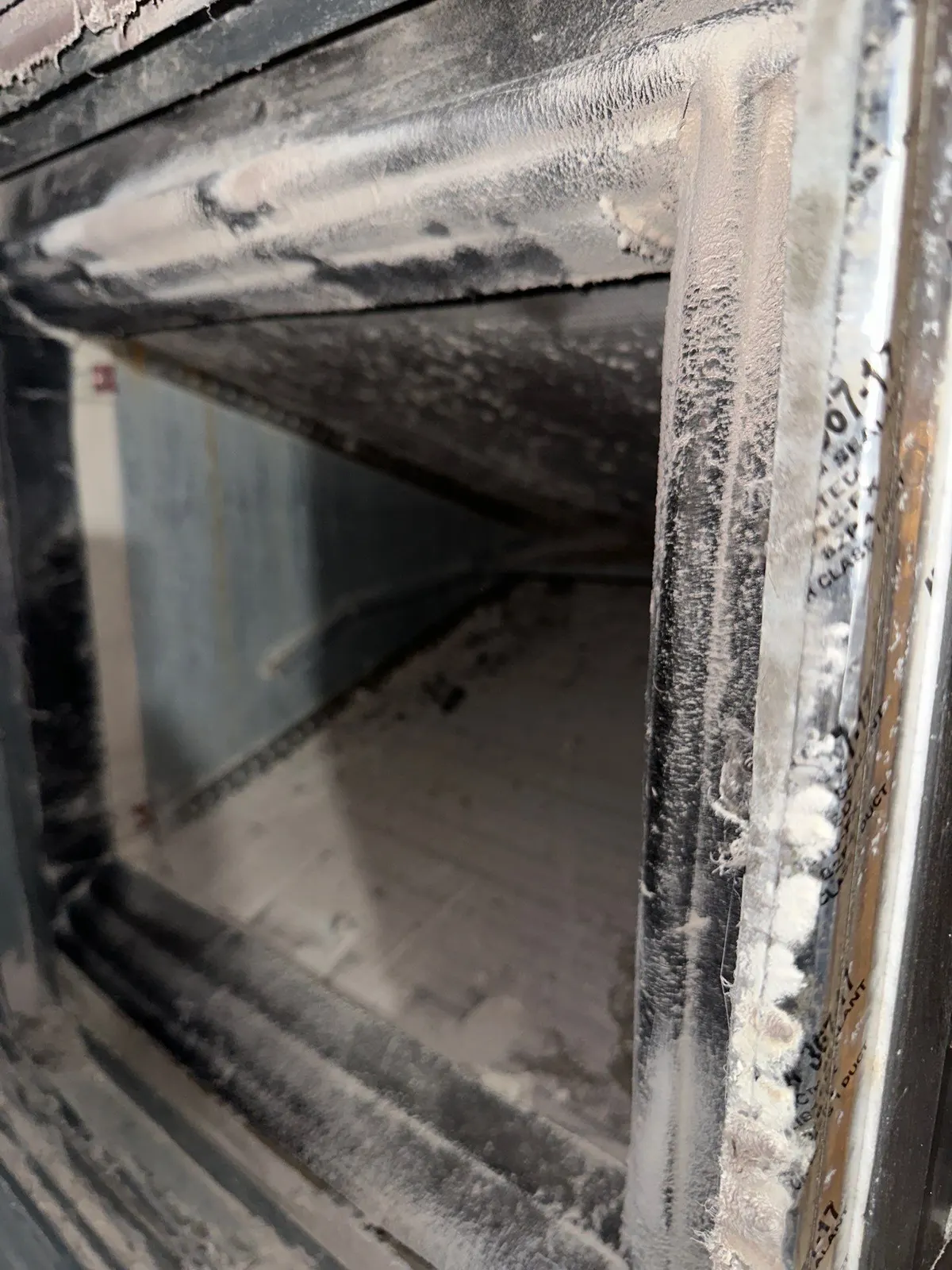 Inside a supply duct opening coated with dust and lint