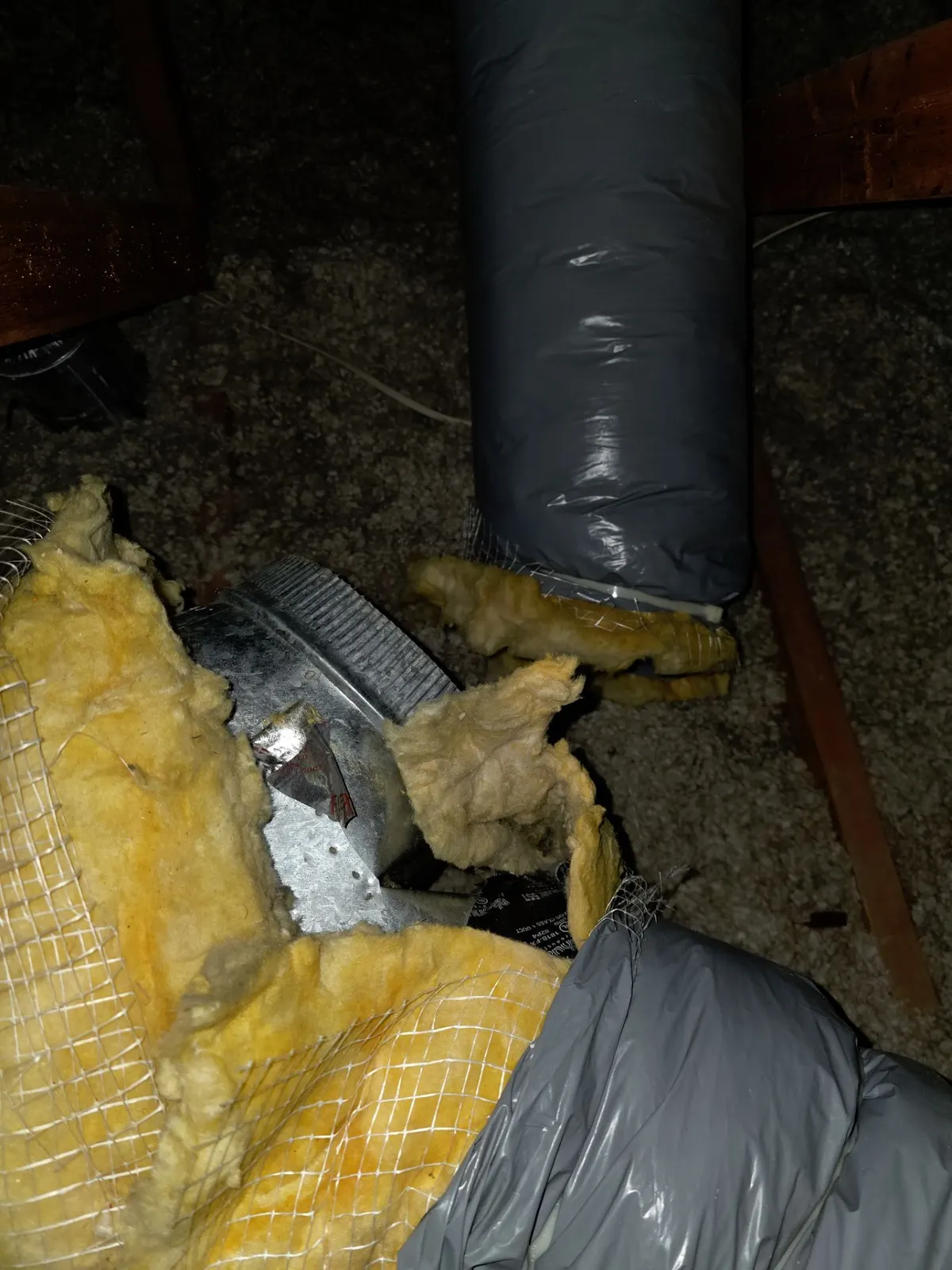 Disconnected attic duct joint with exposed metal collar and torn insulation
