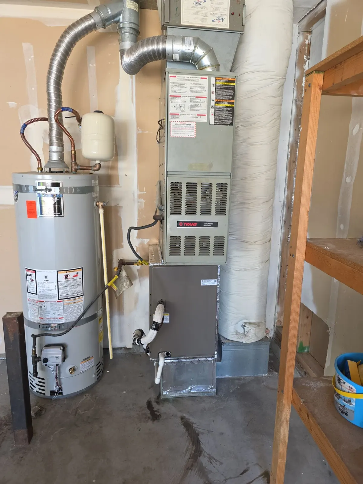 Gas furnace in a garage with a new cased evaporator coil installed, next to a water heater