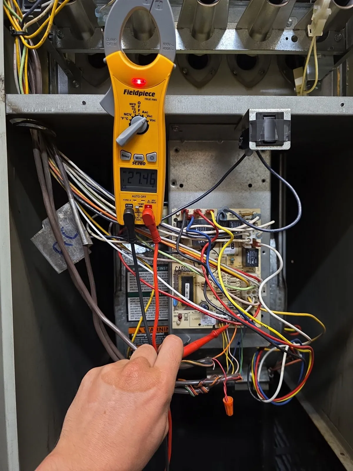 Technician testing furnace control wiring with a clamp meter