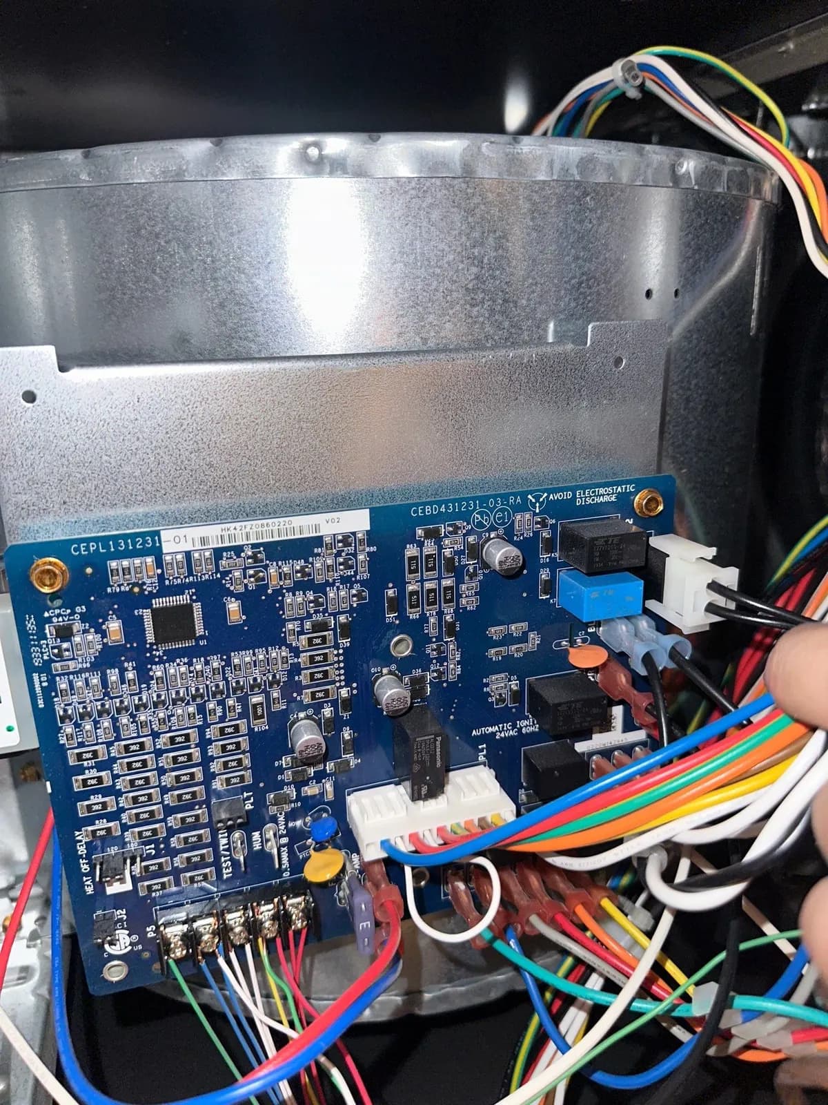 Furnace control circuit board with colored wires connected, mounted beside the blower housing