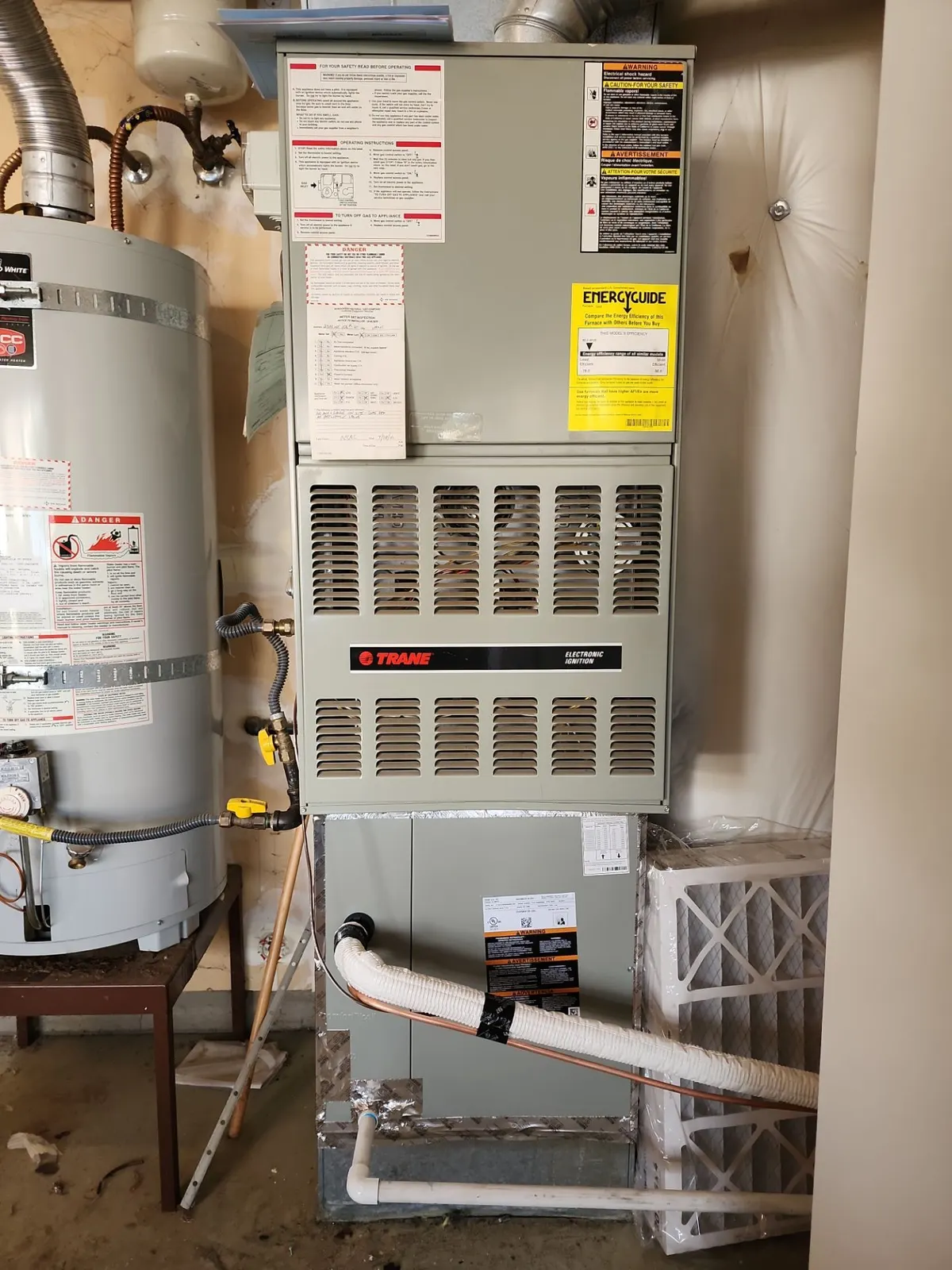 Gas furnace with a new cased evaporator coil and insulated refrigerant line beside a water heater