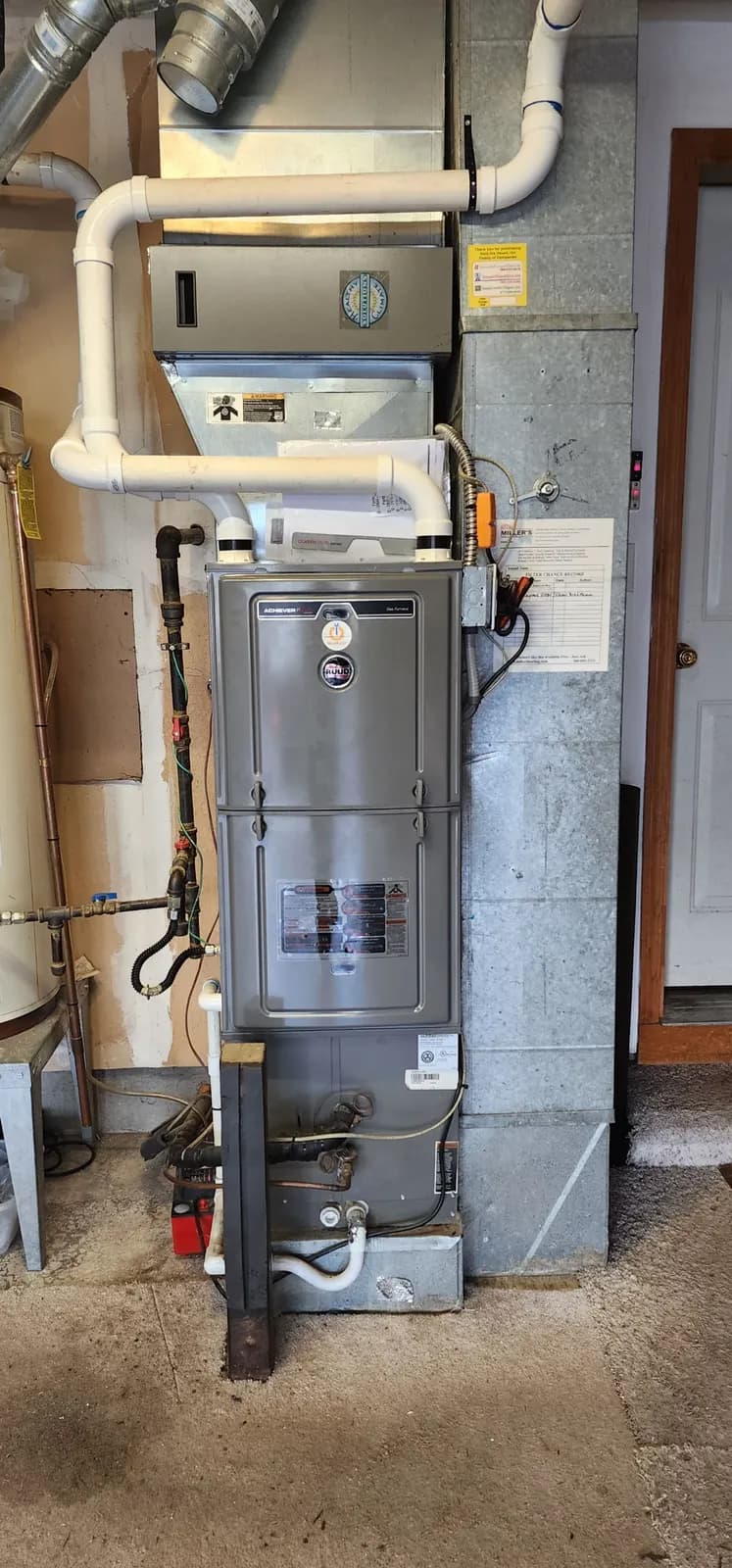 New upflow gas furnace in a garage with white PVC intake and exhaust pipes