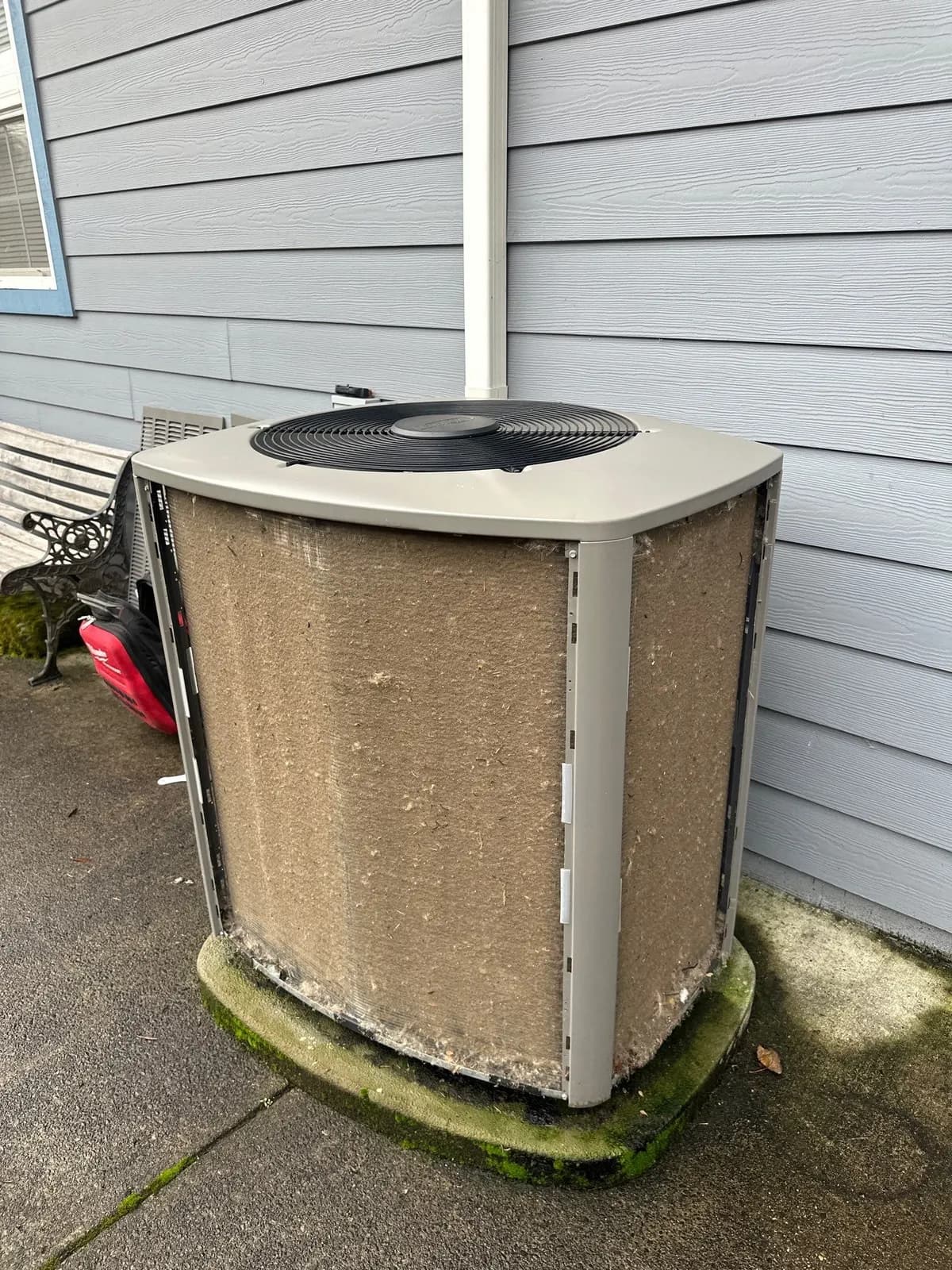 Outdoor AC condenser with its coil completely matted with tan lint and fluff