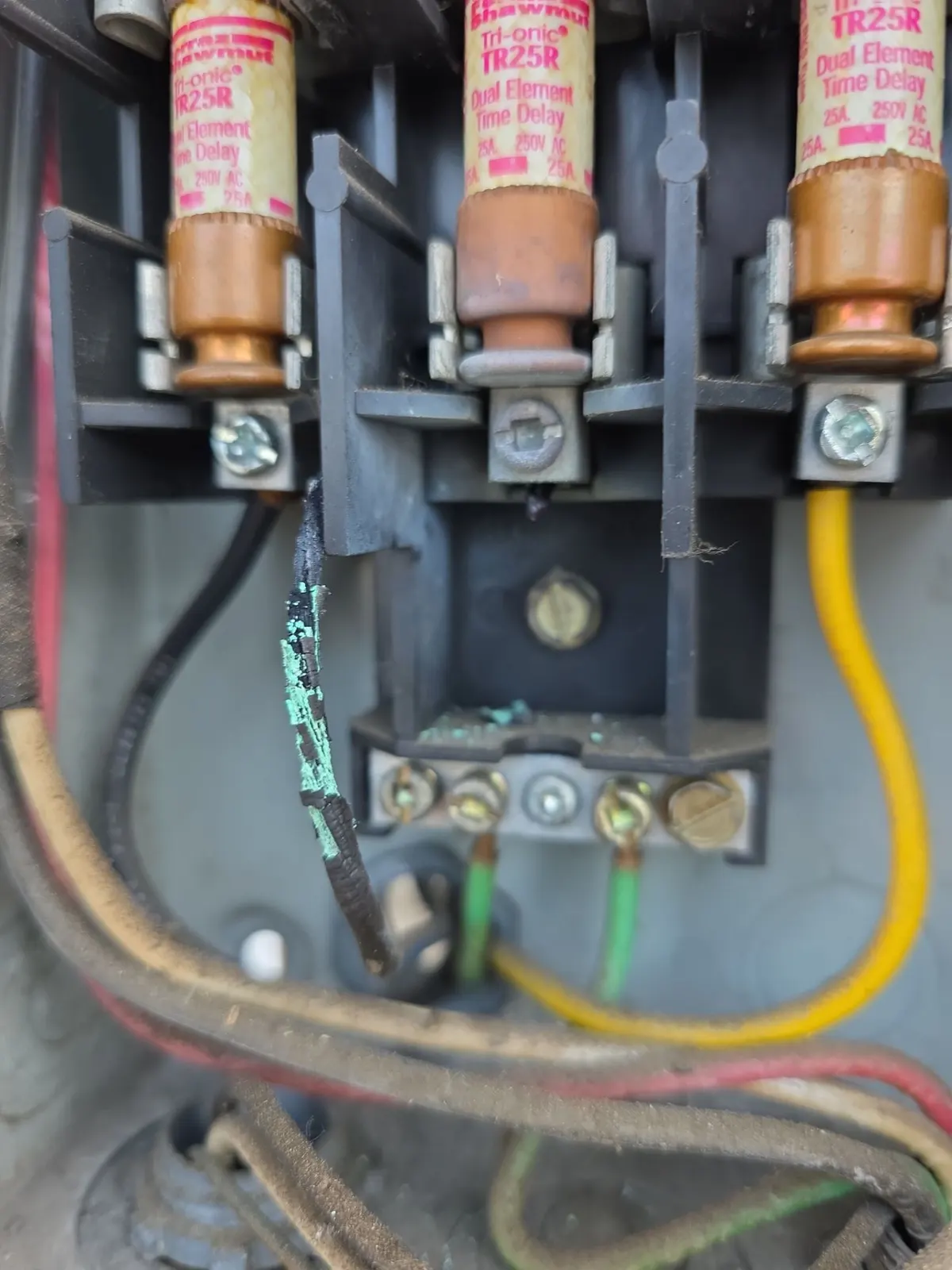 Fused AC disconnect with a melted, charred wire and green corrosion at the terminal block