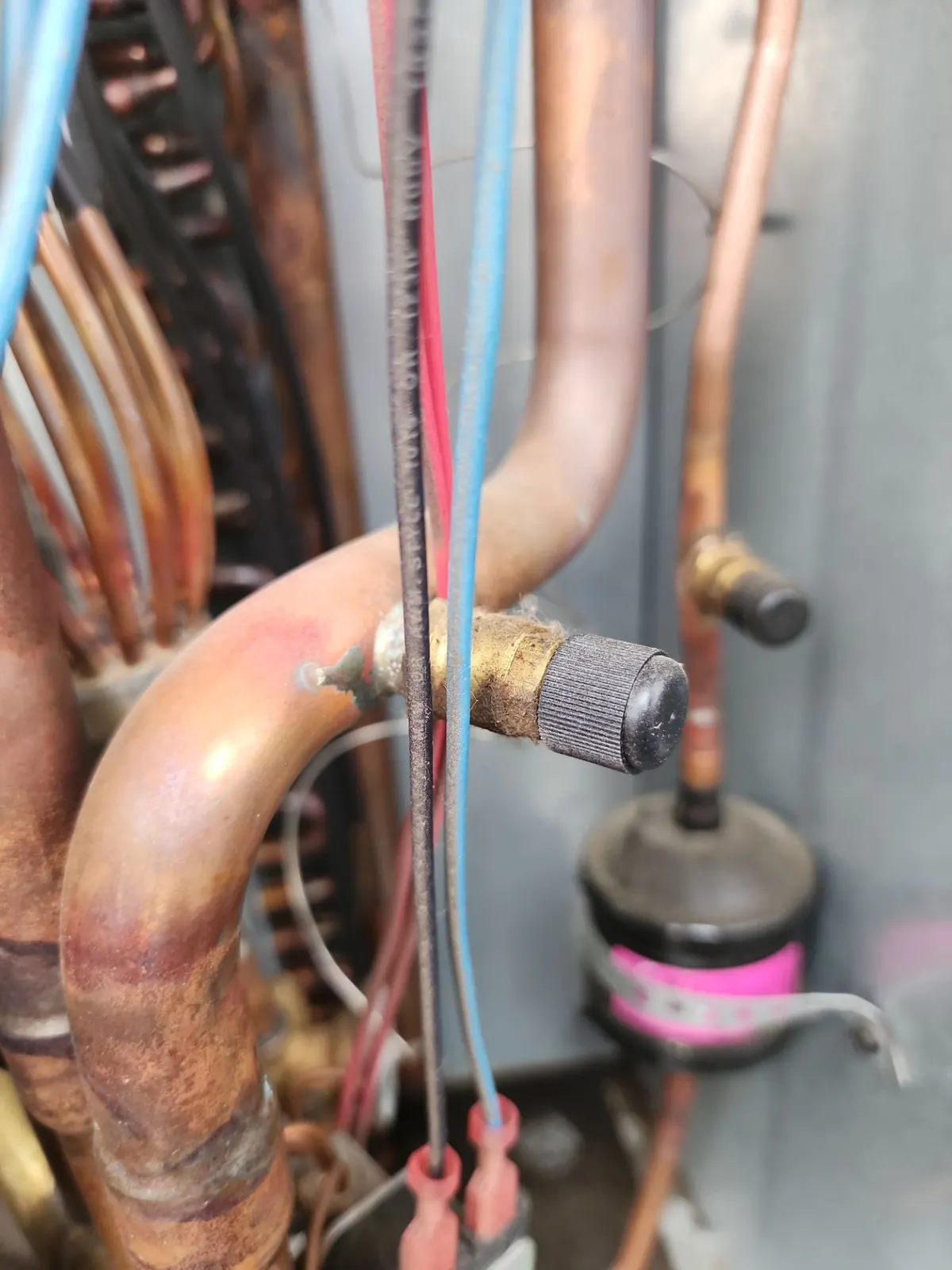 Copper brazed joint with oily residue inside a condensing unit next to a capped service port