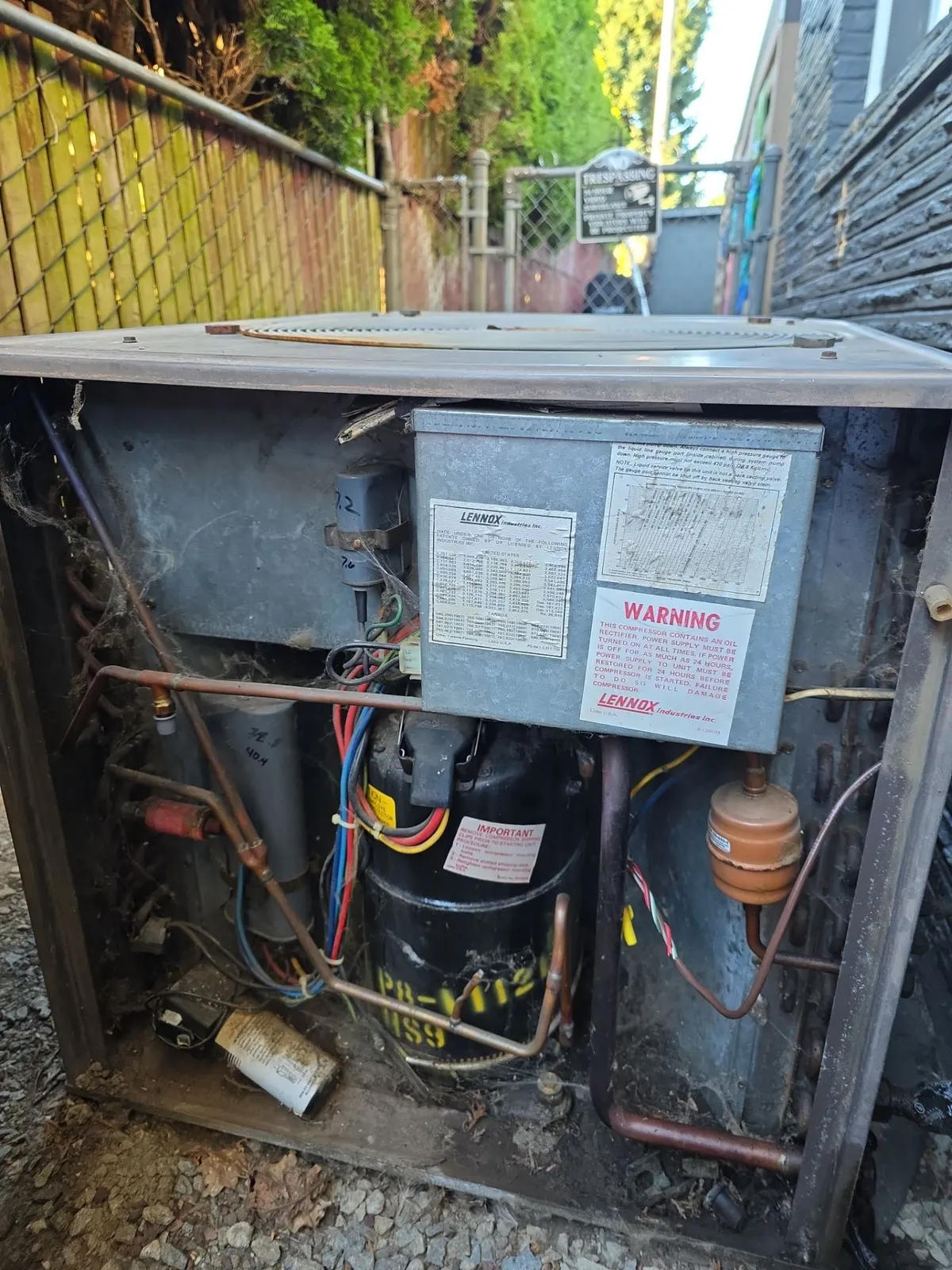 Older outdoor AC condenser with its side panel off showing the compressor and wiring