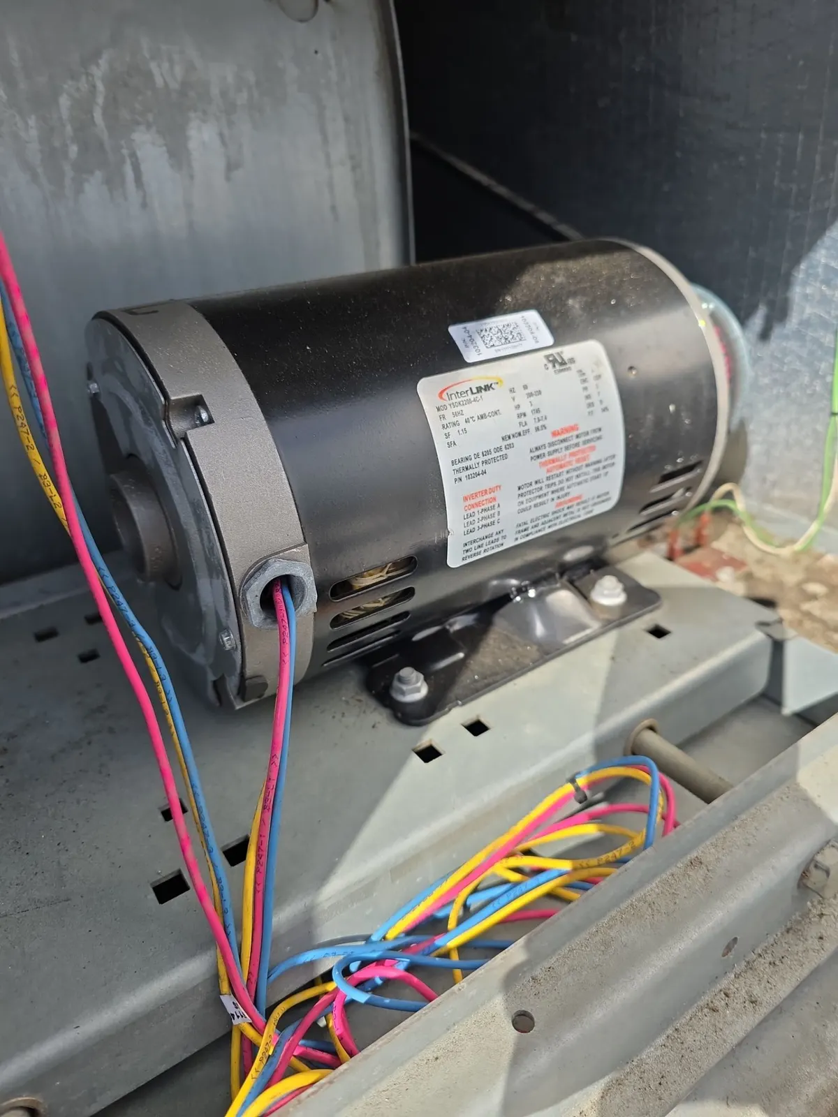 New blower motor bolted inside an open rooftop unit with fresh wiring