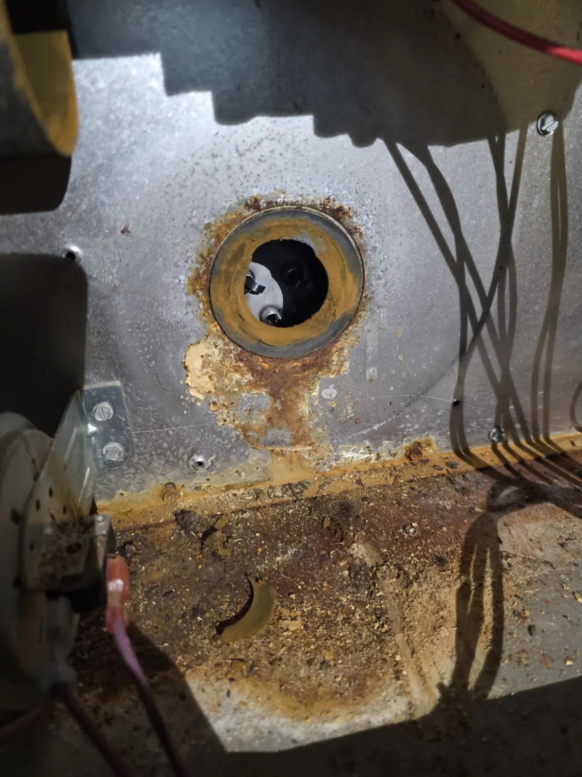 Rust and water staining around the flue opening inside a furnace cabinet