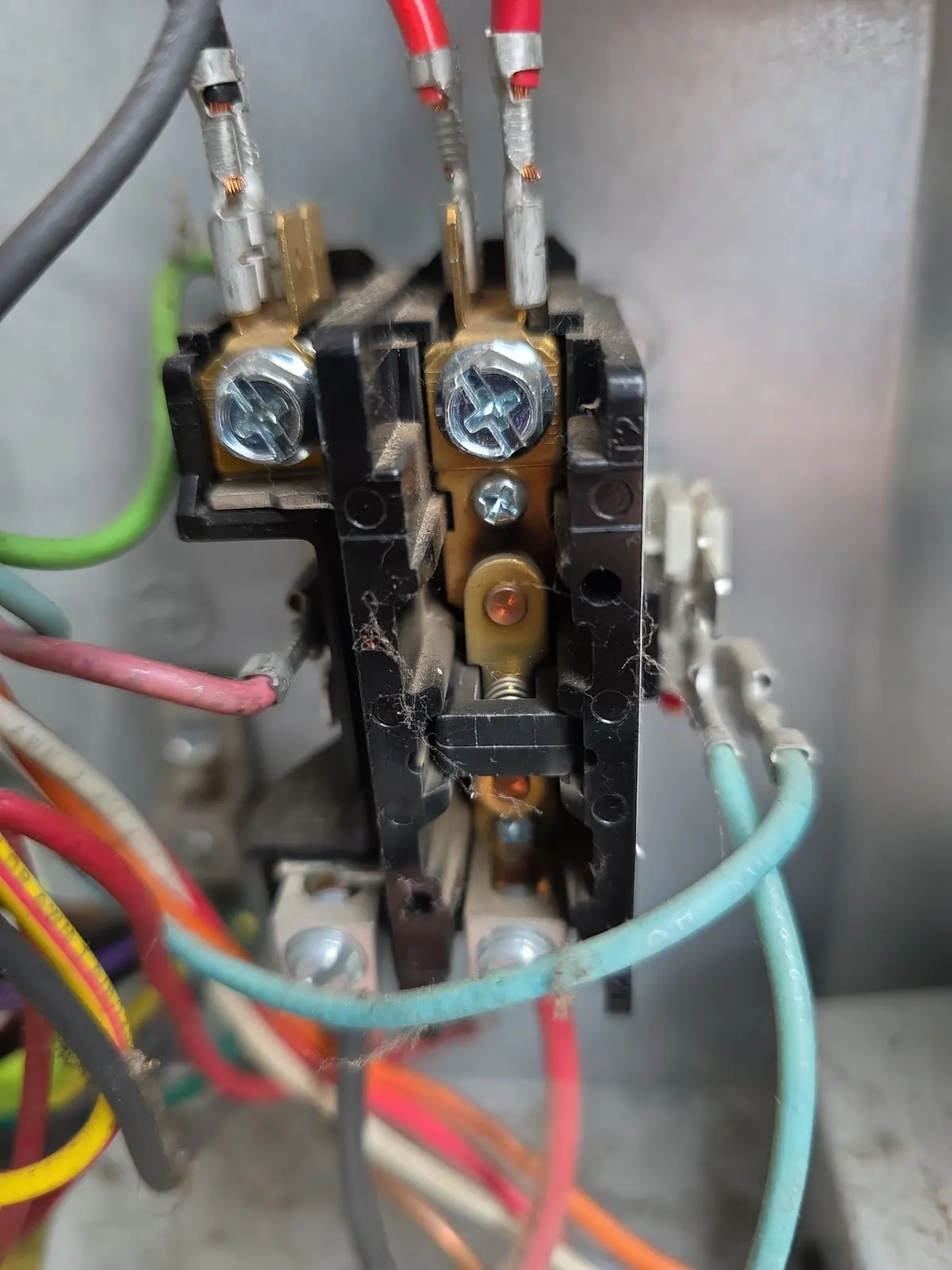 Close-up of a worn contactor with pitted contacts and cobwebs in a condenser control box