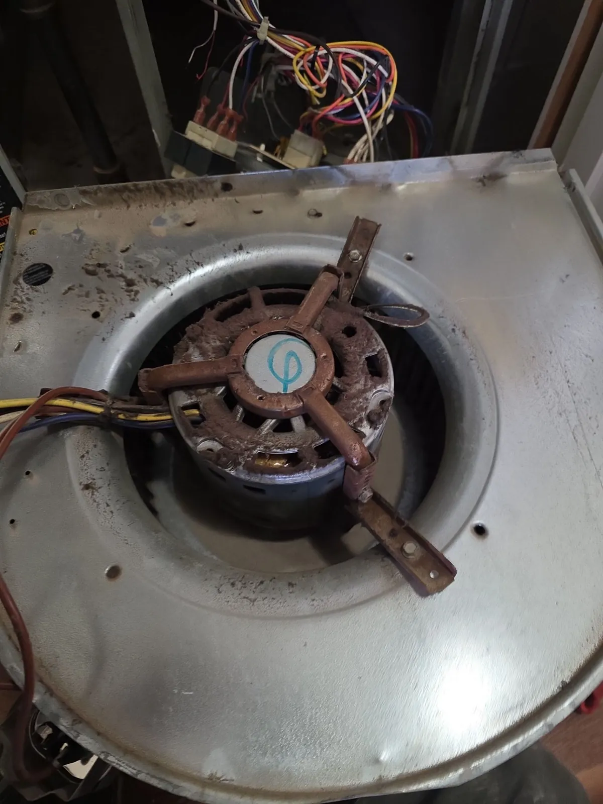 Old rusted blower motor mounted in a furnace blower housing