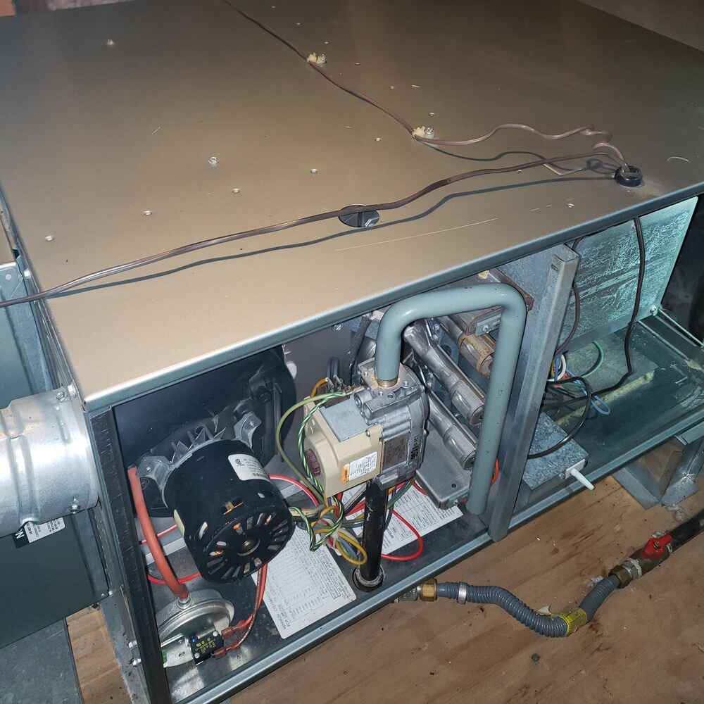 Emergency electric furnace repair with panel removed to expose internal blower motor, heating elements, and wiring during service inspection.