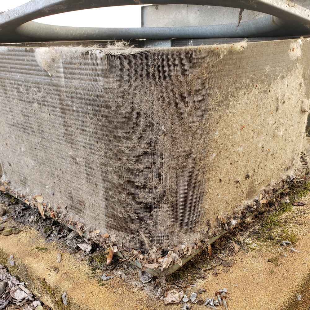 Dirty air conditioner coil covered in debris, indicating poor airflow and the need for immediate air filter replacement and system cleaning.