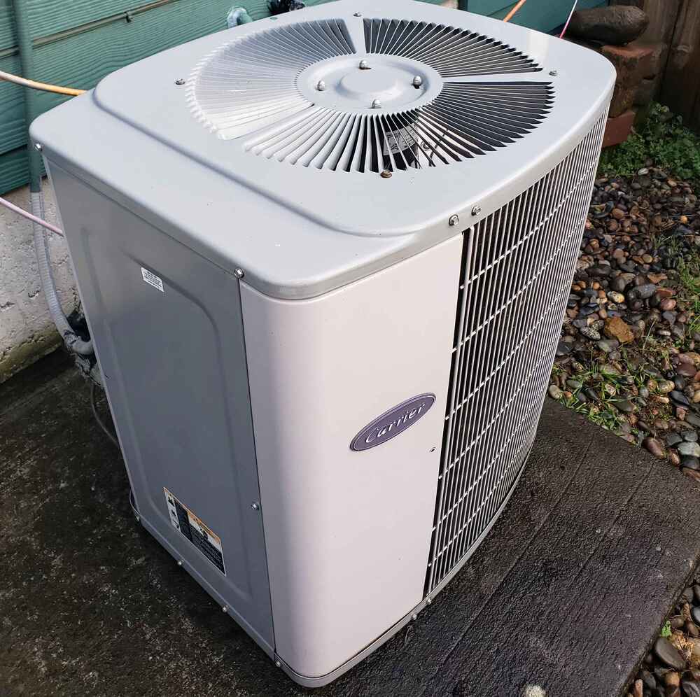 Commercial air conditioner repair on an outdoor Carrier unit, showing a serviced condenser system placed on a level pad near a commercial building.