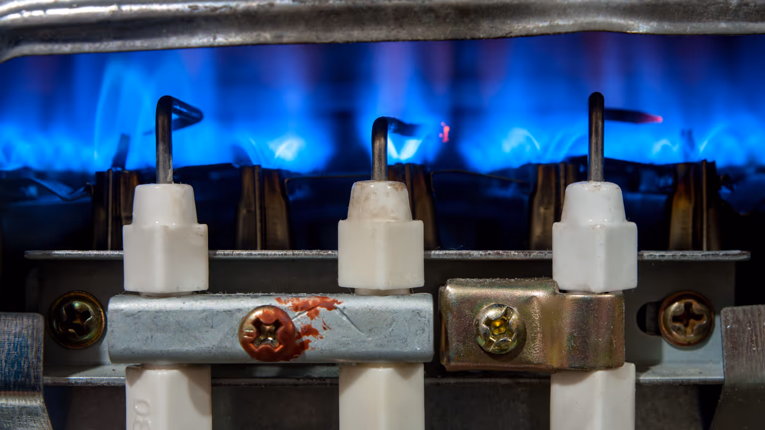 Close-up of gas burner ignition system with blue flame, illustrating cooktop repair and maintenance services for optimal performance and safety.